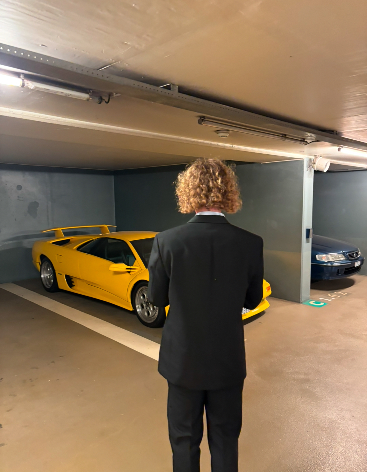 Person in suit looking at yellow sports car